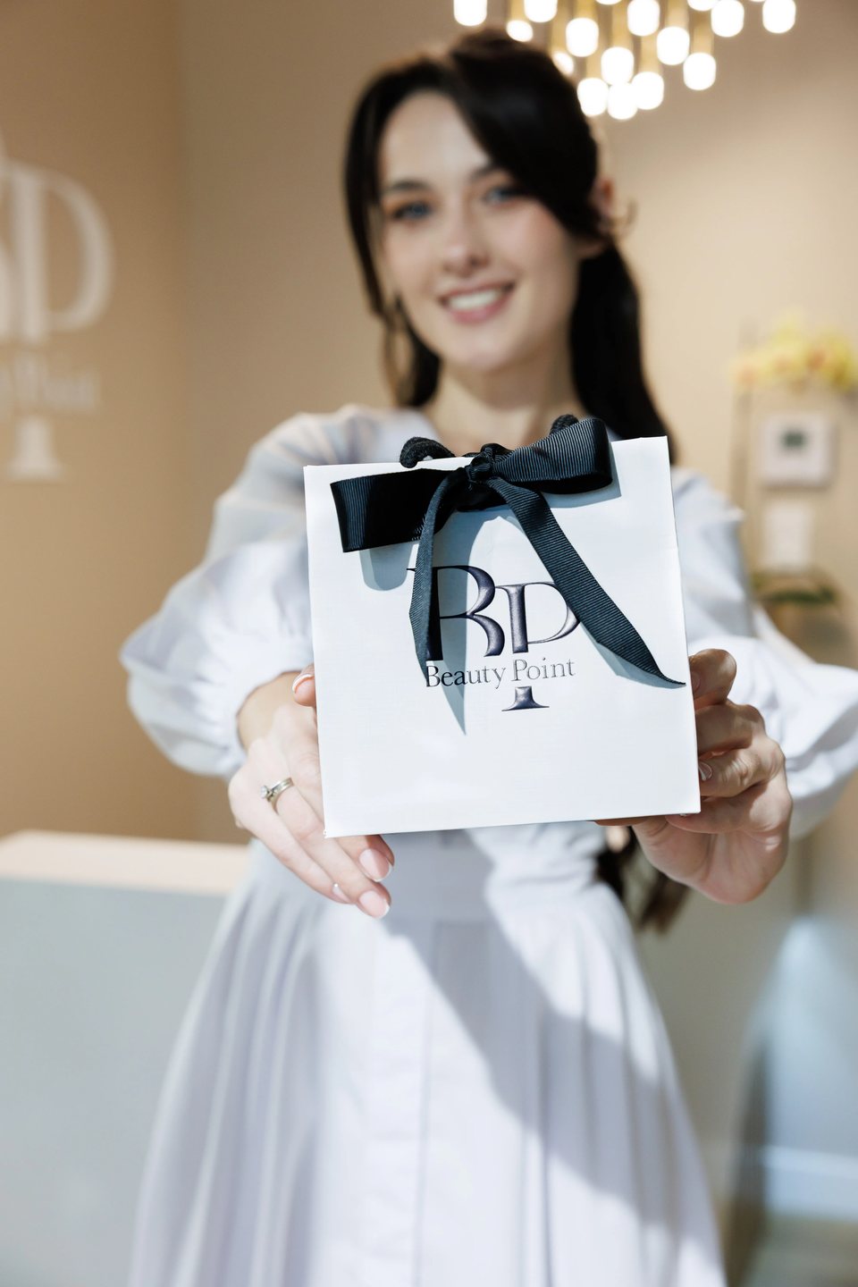 Med-spa owner with a branded gift bag at her clinic